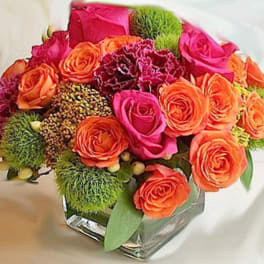Bouquet of orange and pink roses in a clear square vase