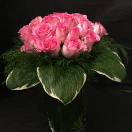 Pink roses arranged in a bouquet with large green leaves