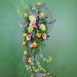 Tall floral arrangement with orange roses, gerbera daisies, and purple blooms