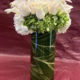 White roses and hydrangeas arranged in a tall glass vase