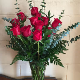 Red roses in a clear glass vase with tall eucalyptus stems