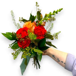 Handheld bouquet of red and peach roses with greenery