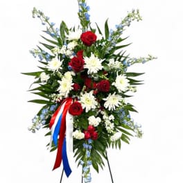 Standing floral spray with red roses, white daisies, and blue accents