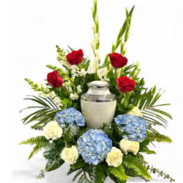 Red and white roses with blue hydrangeas around a silver urn