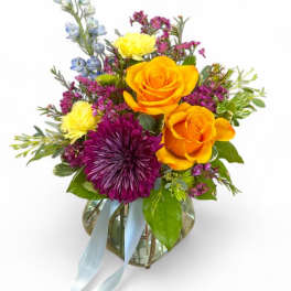 Colorful bouquet of roses, chrysanthemum, and mixed blooms in a glass vase