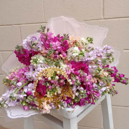 Large bouquet of pink, lavender, and white flowers with a gold handle