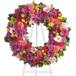 Heart-shaped floral wreath on a white easel with pink, purple, and yellow blooms