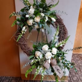 Two white floral wreath arrangements on black stands