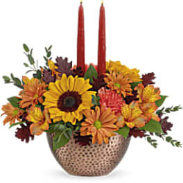 Autumn floral centerpiece with two red taper candles in a patterned vase