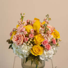 Pink and yellow floral arrangement in a glass vase