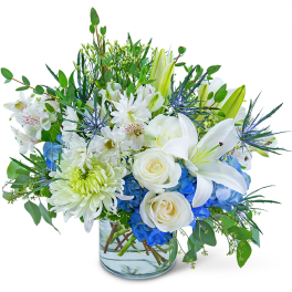 White lilies and roses with blue hydrangeas in a glass vase