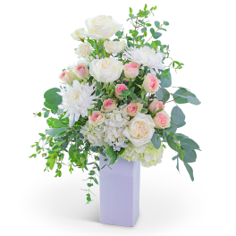 White roses and pink spray roses in a tall white vase