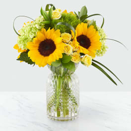Sunflower and yellow rose arrangement in a clear glass vase