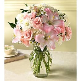 Pink roses and lilies arranged in a clear glass vase