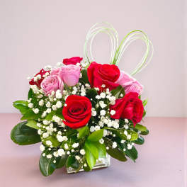 Bouquet of red and pink roses with baby's breath in a clear glass vase