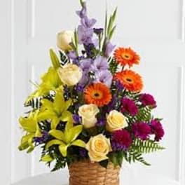 Mixed bouquet in a woven basket with lilies, roses, and gerbera daisies