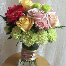 Mixed bouquet of roses, carnations, and daisies in a glass vase