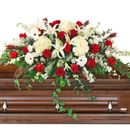 Floral casket spray with red roses and white lilies on a wooden casket