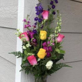 Tall bouquet of pink, yellow, white, and purple flowers in a glass vase