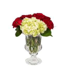 Red roses and pale hydrangeas in a clear glass vase