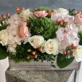 Pink and white floral arrangement in a wooden box