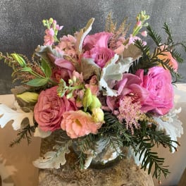 Pink and peach floral arrangement in a glass vase with silvery foliage