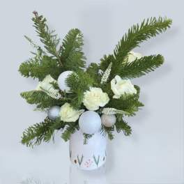 White roses and evergreen branches arranged in a decorated vase with silver ornaments