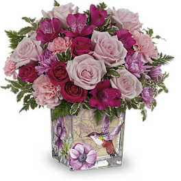Pink and magenta bouquet in a square glass vase with a hummingbird design