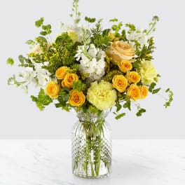 Yellow and white flower arrangement in a clear glass vase