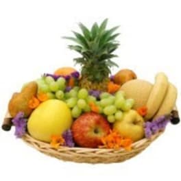 Fruit basket with pineapple, grapes, apples, and melons in a wicker tray