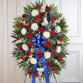 Standing floral spray with red, white, and blue flowers on a ribboned easel