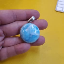 Blue round pendant held in a hand
