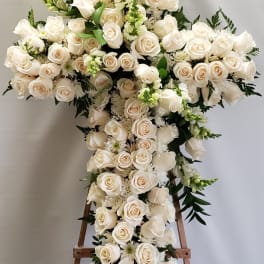 Large white rose cross arrangement on a wooden stand