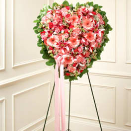 Heart-shaped pink floral standing spray on an easel with ribbon