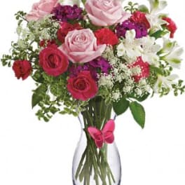 Bouquet of pink and red roses with white flowers in a clear glass vase