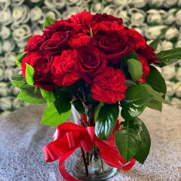 Red roses and carnations in a glass vase with a red ribbon