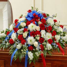 Large red and white floral casket spray with blue and red ribbons