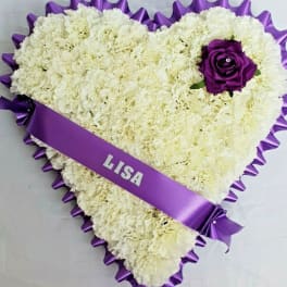 Heart-shaped white carnation arrangement with a purple rose and ribbon