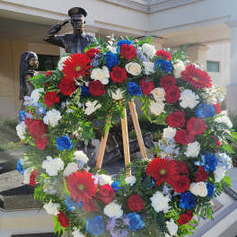 Large patriotic floral wreath on a wooden easel with red, white, and blue flowers