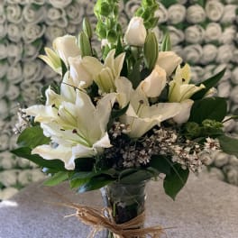 White lilies and roses in a glass vase with raffia tie