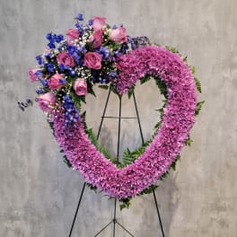 Heart-shaped floral wreath with pink roses and purple chrysanthemums on a stand