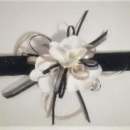 White flower corsage with black ribbon on a wristband