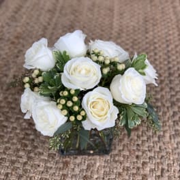 White rose bouquet in a square glass vase with berry accents