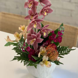 Pink orchid arrangement in a white textured vase
