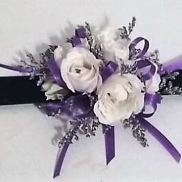 White floral wrist corsage with purple ribbon on a black band