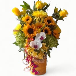 Tall yellow sunflower and rose arrangement with white orchids in a wrapped vase with ribbons and butterflies