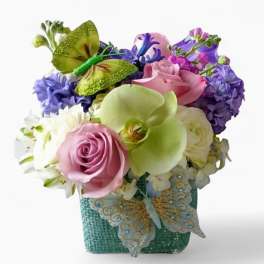 Square pastel flower arrangement with roses, orchid, hyacinth and decorative butterflies in a teal container