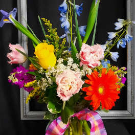 Colorful mixed bouquet in a glass vase with a plaid ribbon