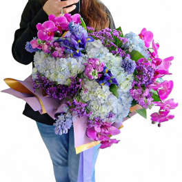 Large bouquet of pink, purple, and blue flowers wrapped in pastel paper