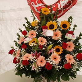 Heart-shaped red balloon above a mixed flower basket with roses and daisies